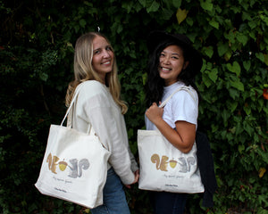 two young women with matching squirrel canvas tote bags